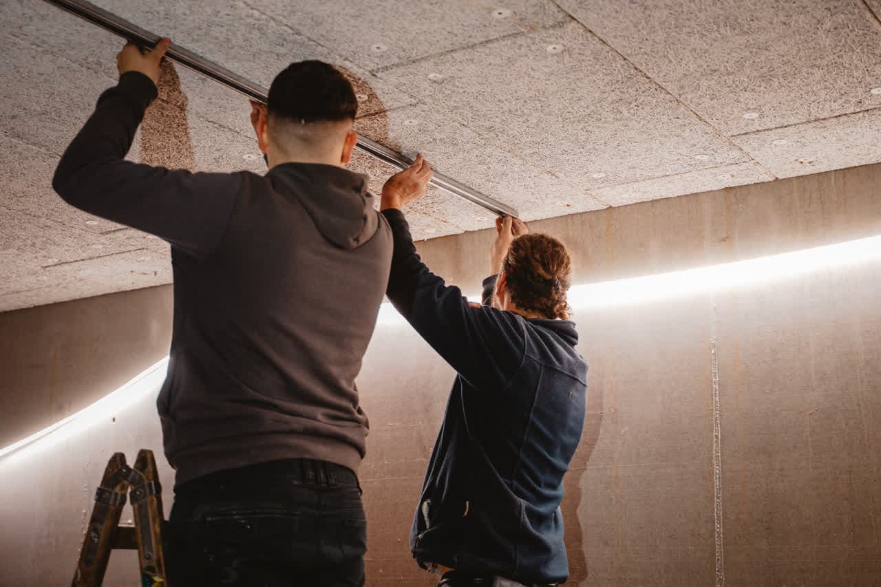 Zwei Monteure von Installationstechnik Wels arbeiten gemeinsam an einer Deckeninstallation