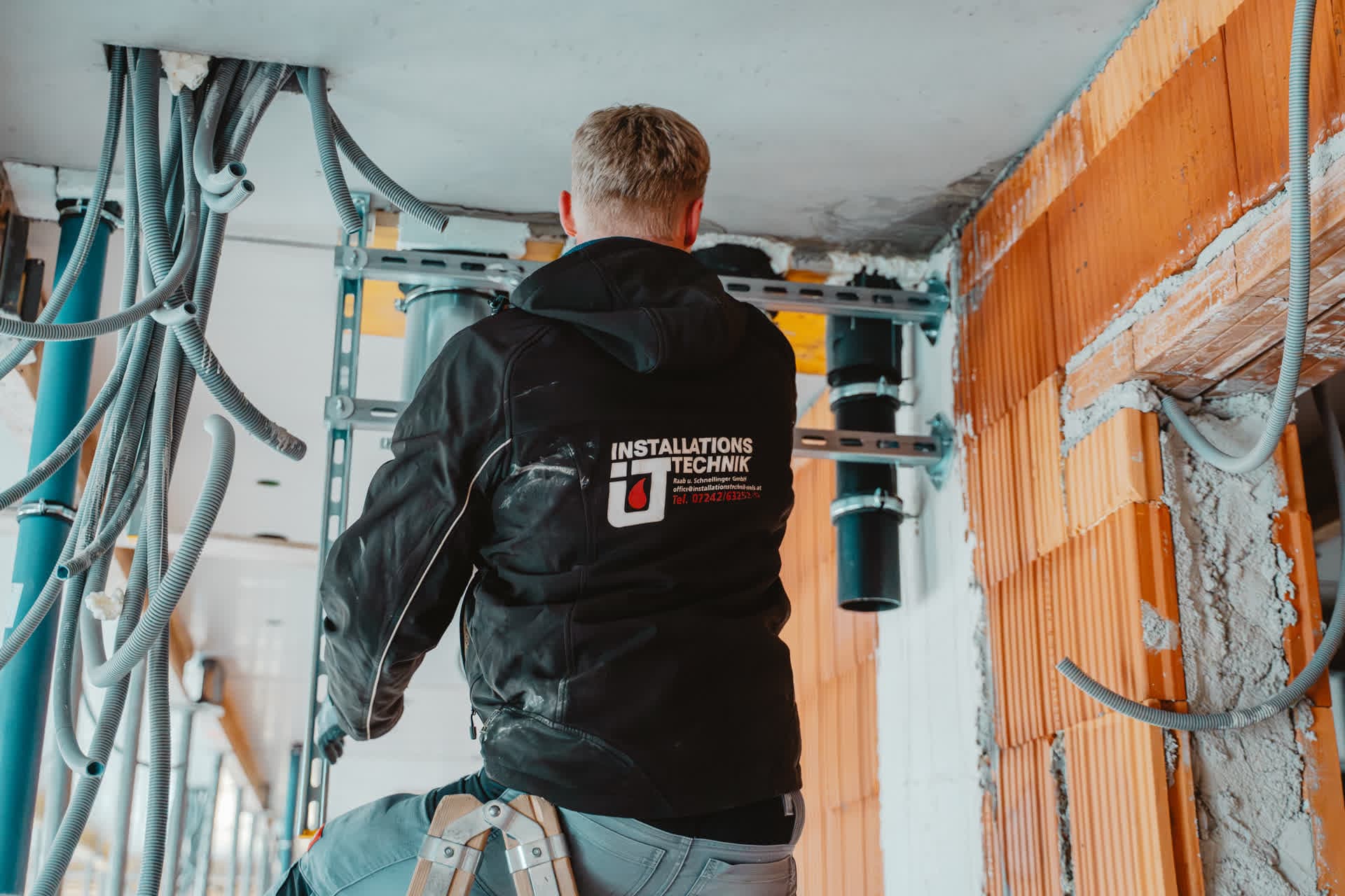 Monteur von Installationstechnik Wels mit Firmenjacke auf der Baustelle